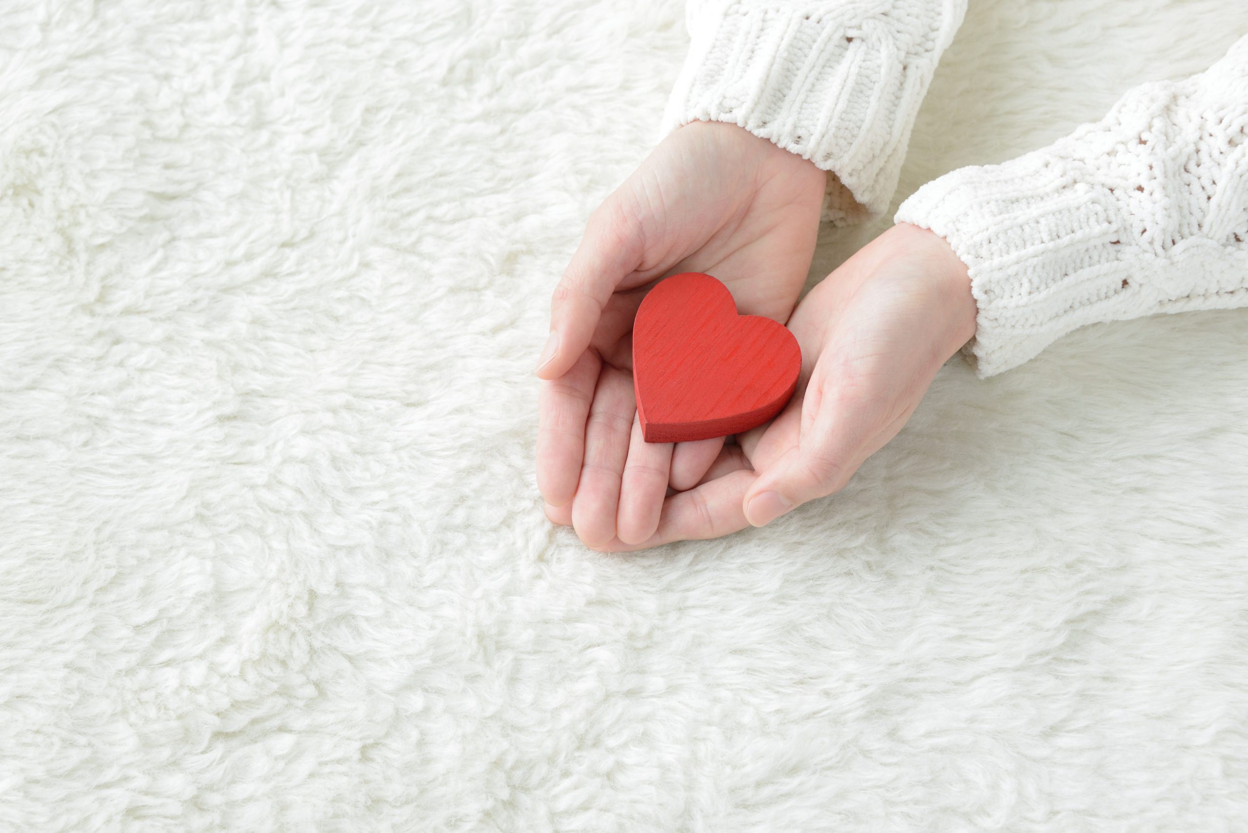 Hands holding a red toy heart