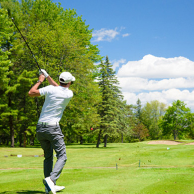 Golfer swings at a golf ball on a clear, sunny day