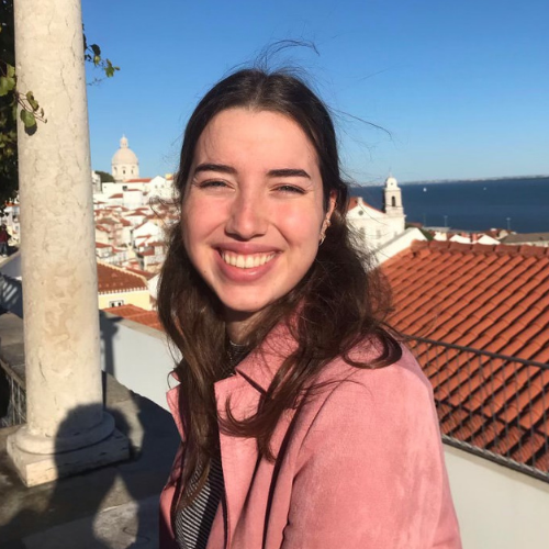 Young woman sitting near a post by the Portuguese seaside